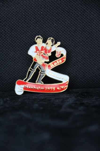 Eine Anstecknadel mit einem Mann, der auf schwarzem Hintergrund eine Frau im Arm hält.