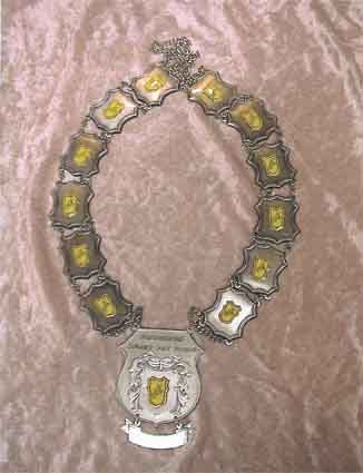 Auf einem rosa Tuch sitzt eine Halskette mit einem Wappen darauf.