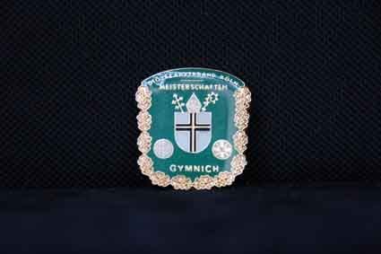 Auf einer schwarzen Fläche befindet sich eine grüne Plakette mit einem Kreuz darauf.