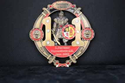 Auf einer schwarzen Fläche liegt eine Medaille mit einem Ritter darauf.