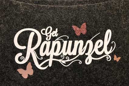 Eine Nahaufnahme eines T-Shirts mit den Worten „Get Rapunzel“ und Schmetterlingen darauf.