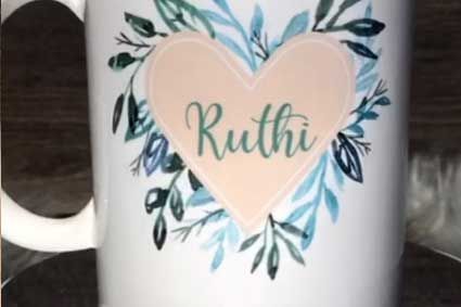 Eine weiße Tasse mit einem Herz und dem Namen Ruthi darauf.