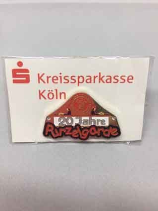 Auf einem Tisch liegt eine Anstecknadel mit dem Logo der Kreissparkasse Köln.