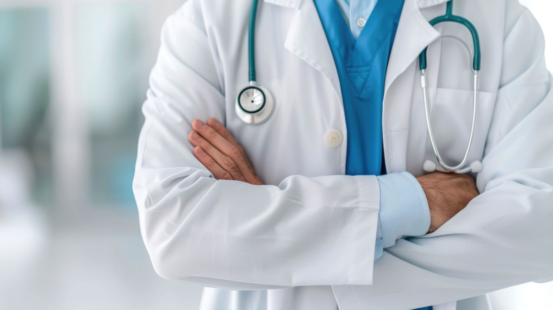 Un médecin, les bras croisés, vêtu d'une blouse blanche et tenant un stéthoscope.