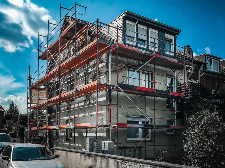 Ein im Bau befindliches Gebäude mit Gerüst darum und einem davor geparkten Auto.