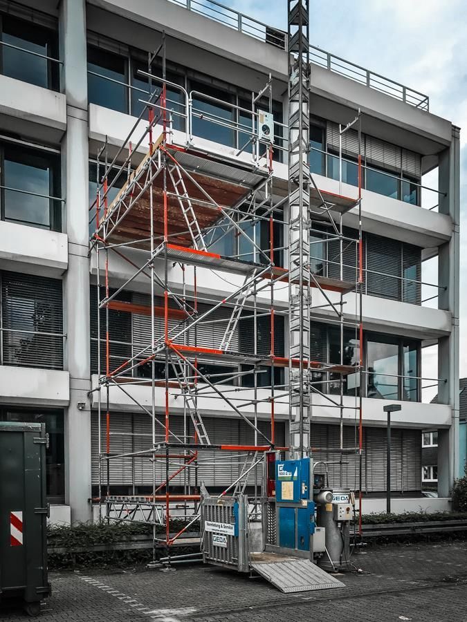 Ein im Bau befindliches Gebäude mit Gerüst und einem Aufzug davor.