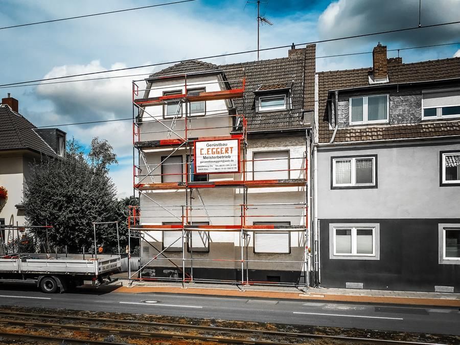 Ein LKW steht vor einem Gebäude mit Gerüst darauf.