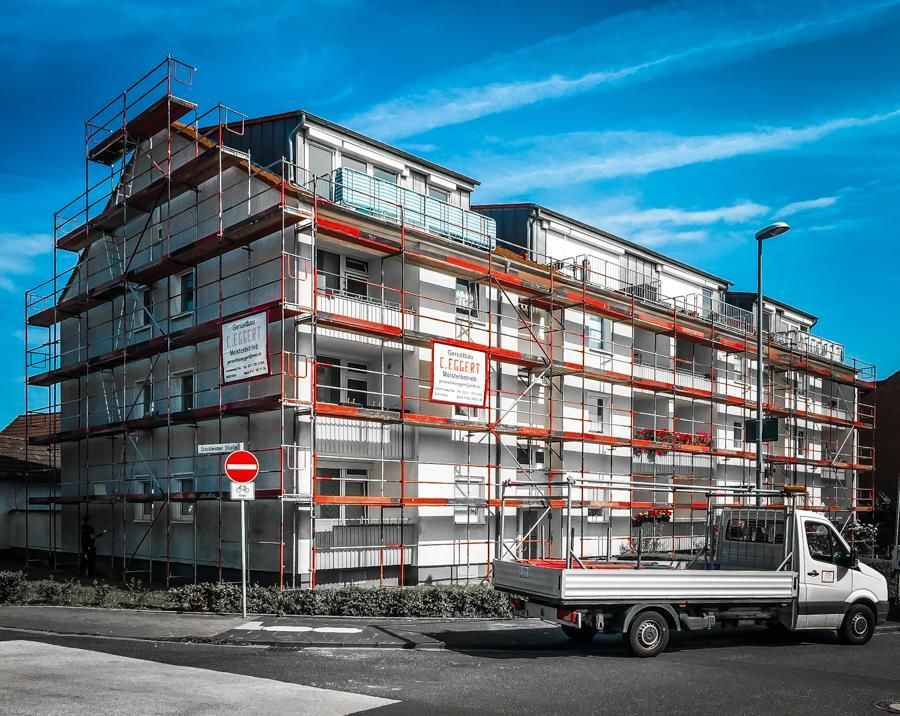 Ein weißer Lastwagen parkt vor einem im Bau befindlichen Gebäude.