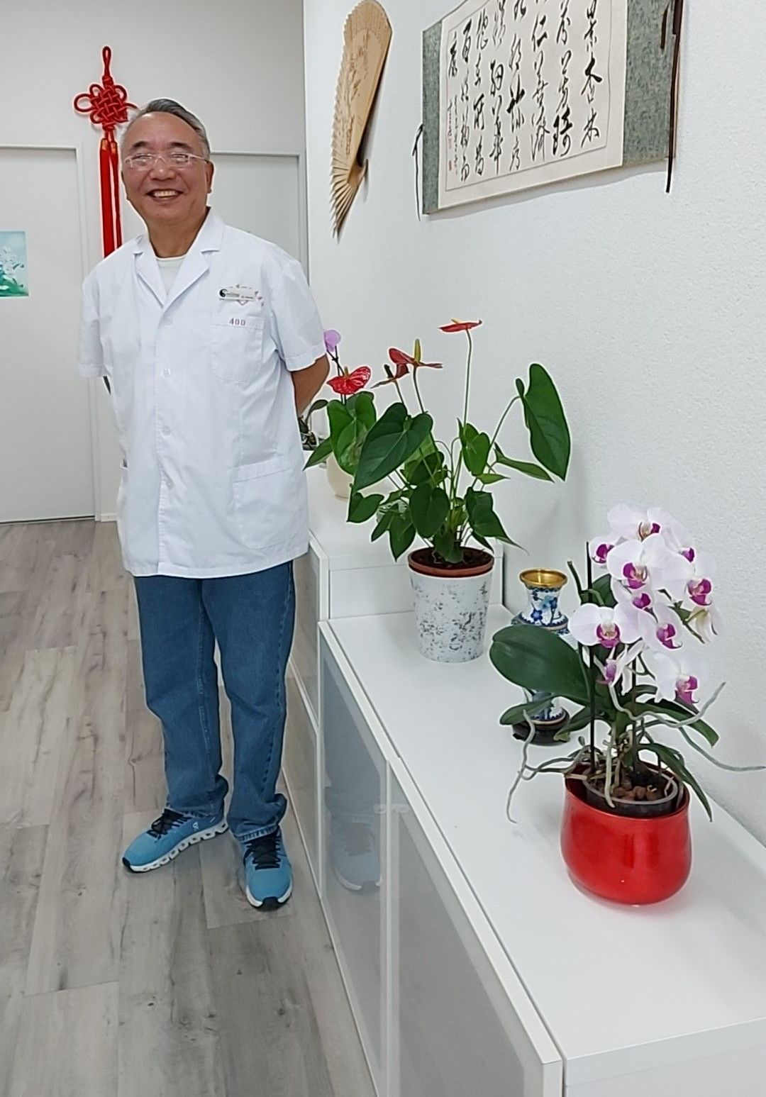A man stands in front of a sign that says traditionelle chinesische medizin