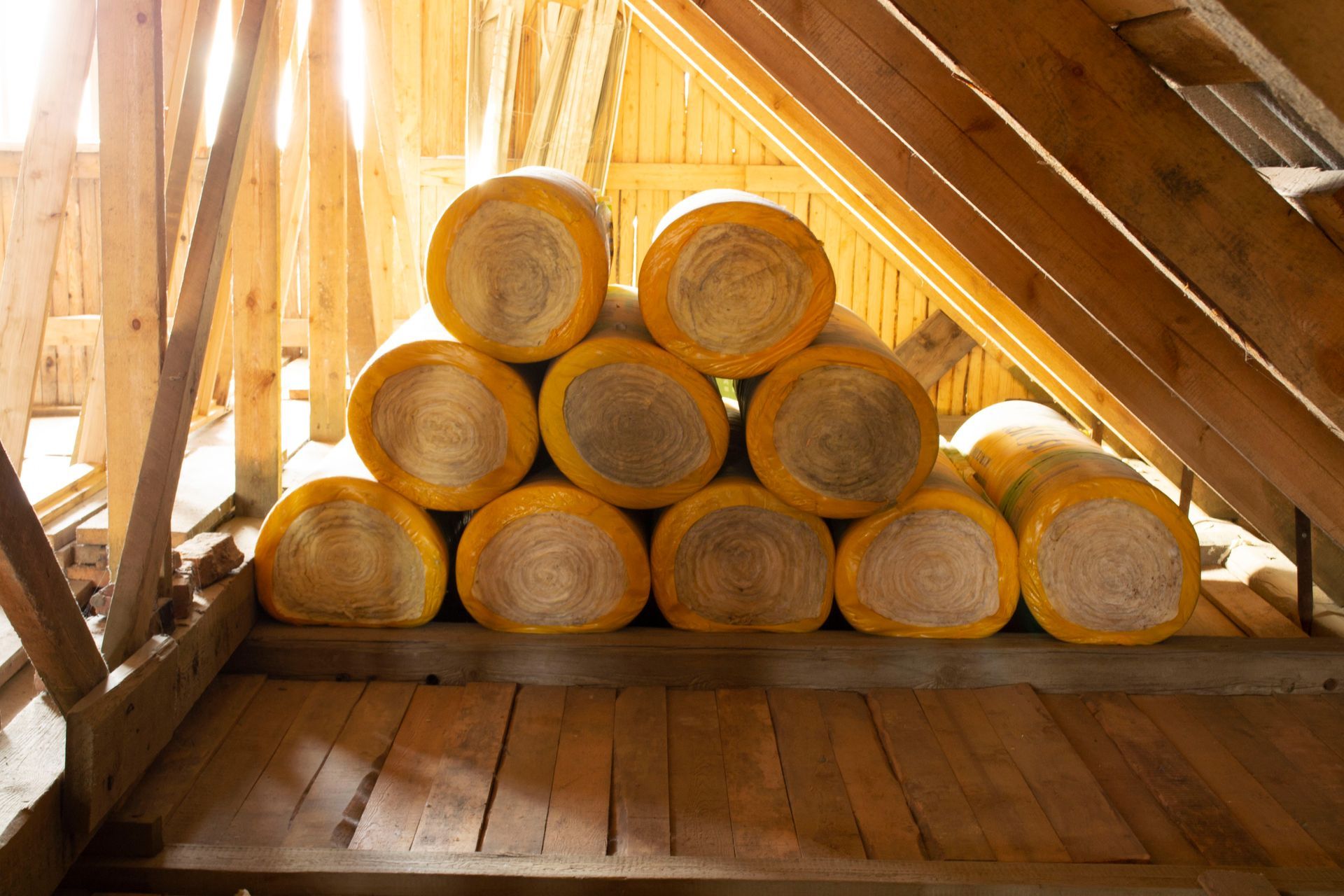 Isolants en rouleaux posés sur un plancher en bois dans un grenier en bois.