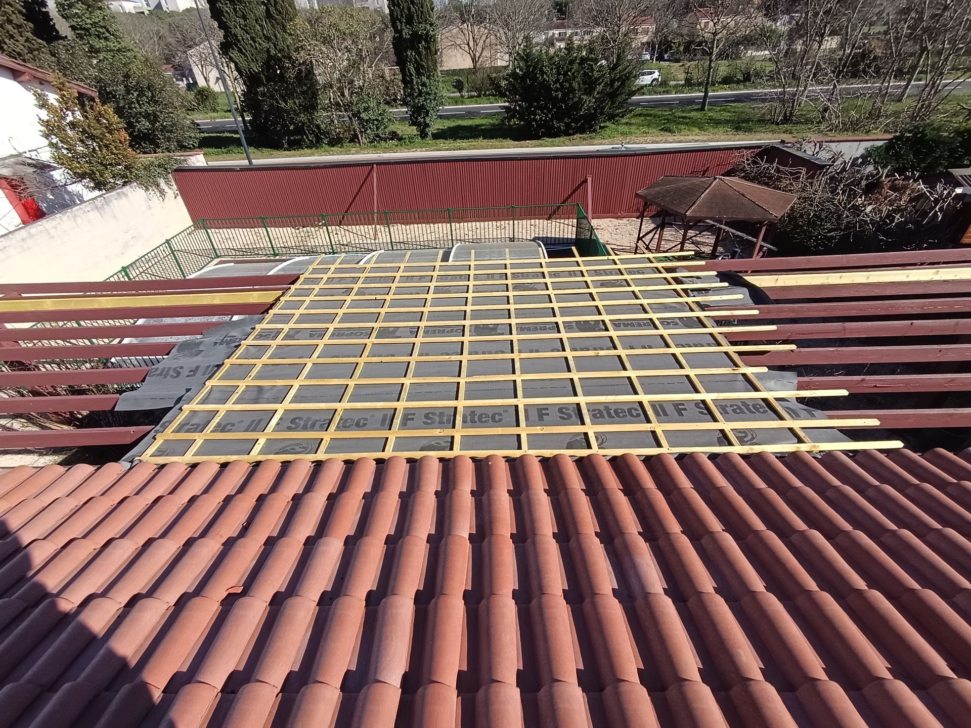 Charpente en bois, écran sous toiture et tuiles en terre cuite, chantier en cours.