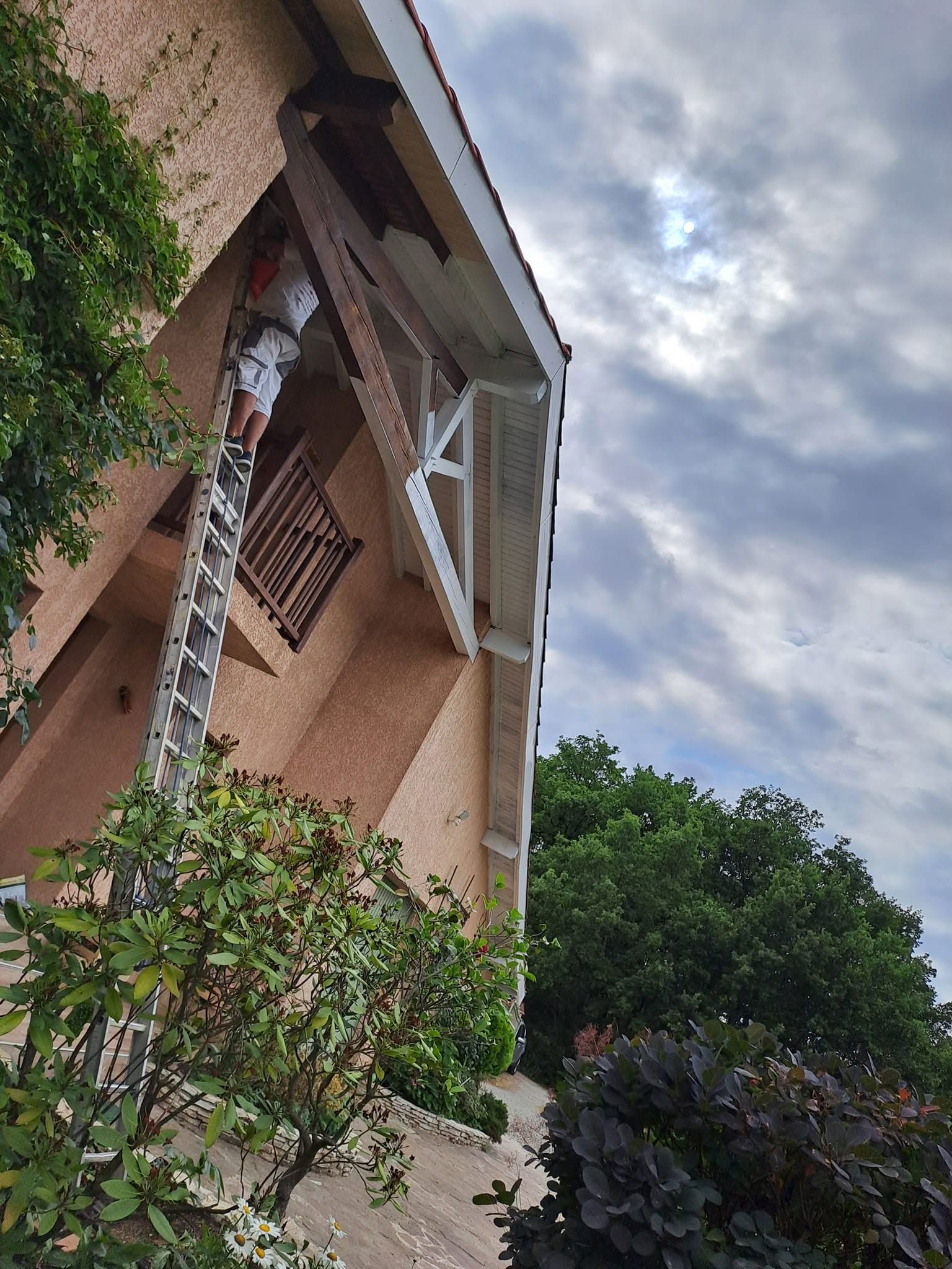 Avancée de toit de maison en cours de rénovation, sous un ciel nuageux.