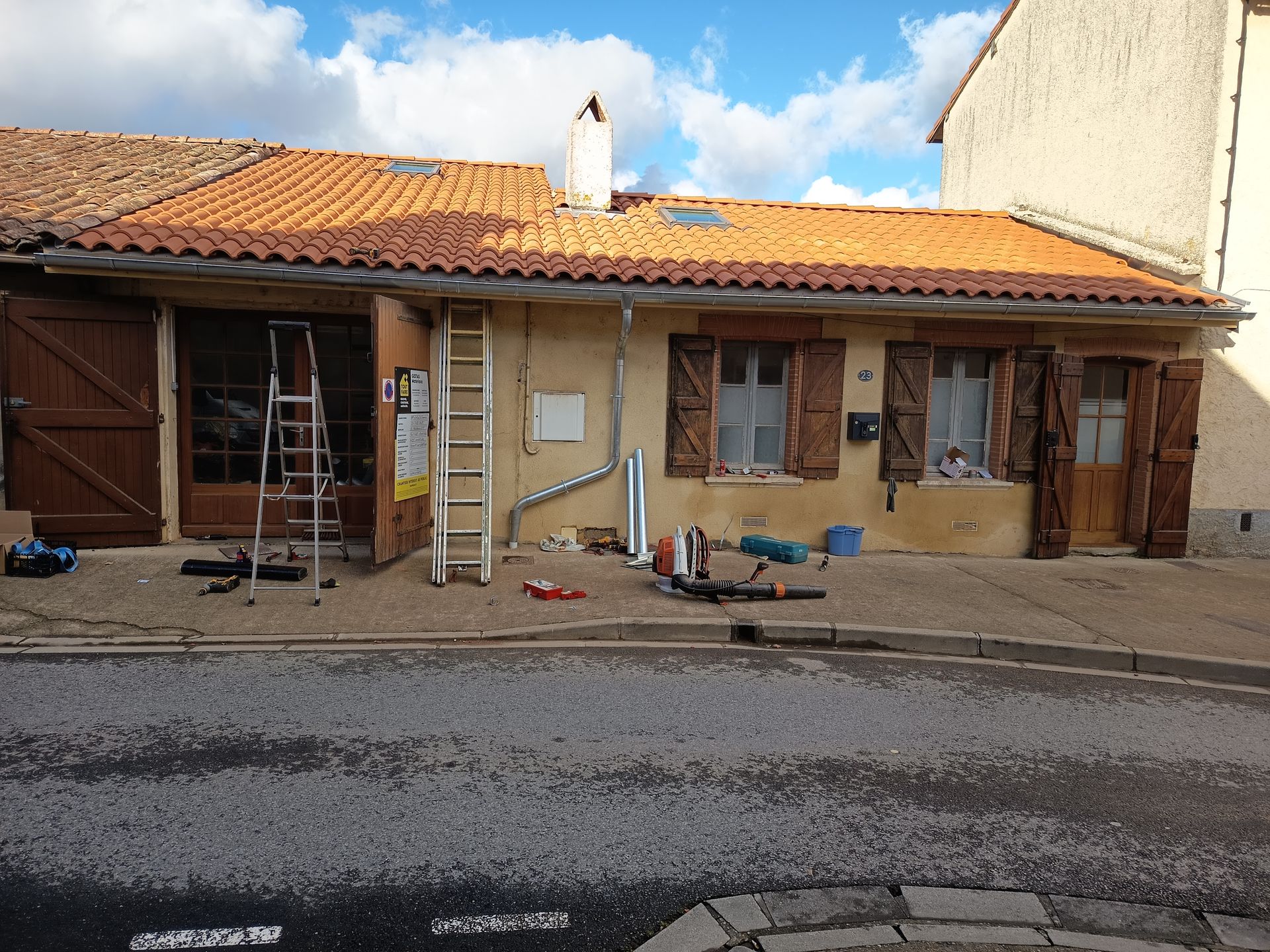 Maisons en cours de rénovation, aux murs beiges et aux toits de tuiles orange, le long d'une rue.