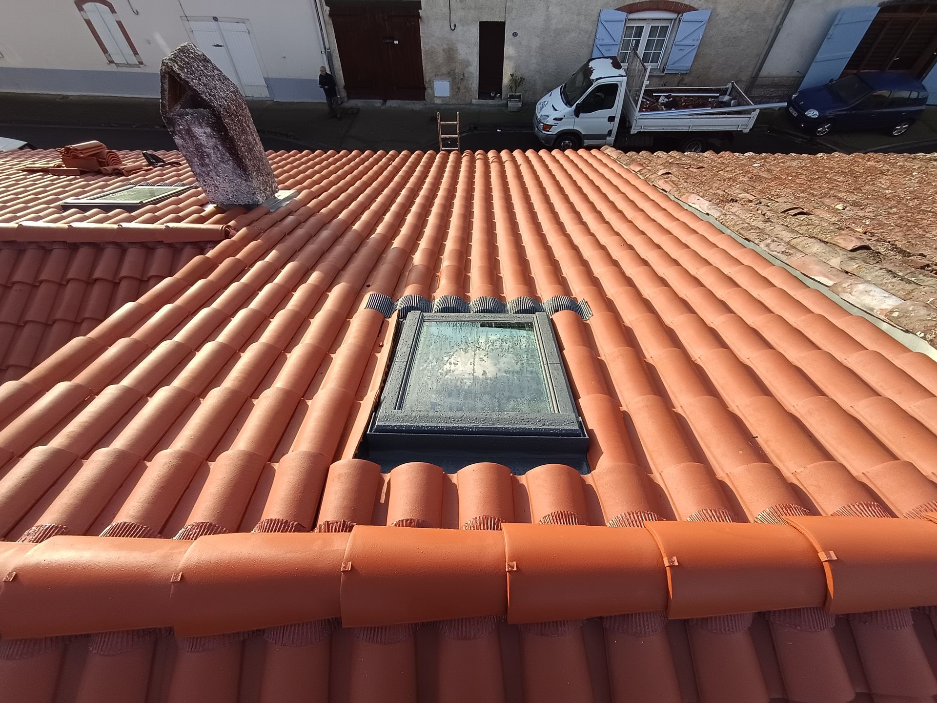 Toiture en tuiles rouges avec une fenêtre de toit, vue du dessus.