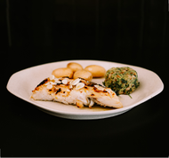 Prato de bacalhau com batatas assadas, azeitonas pretas e salsa em uma tigela de terracota.