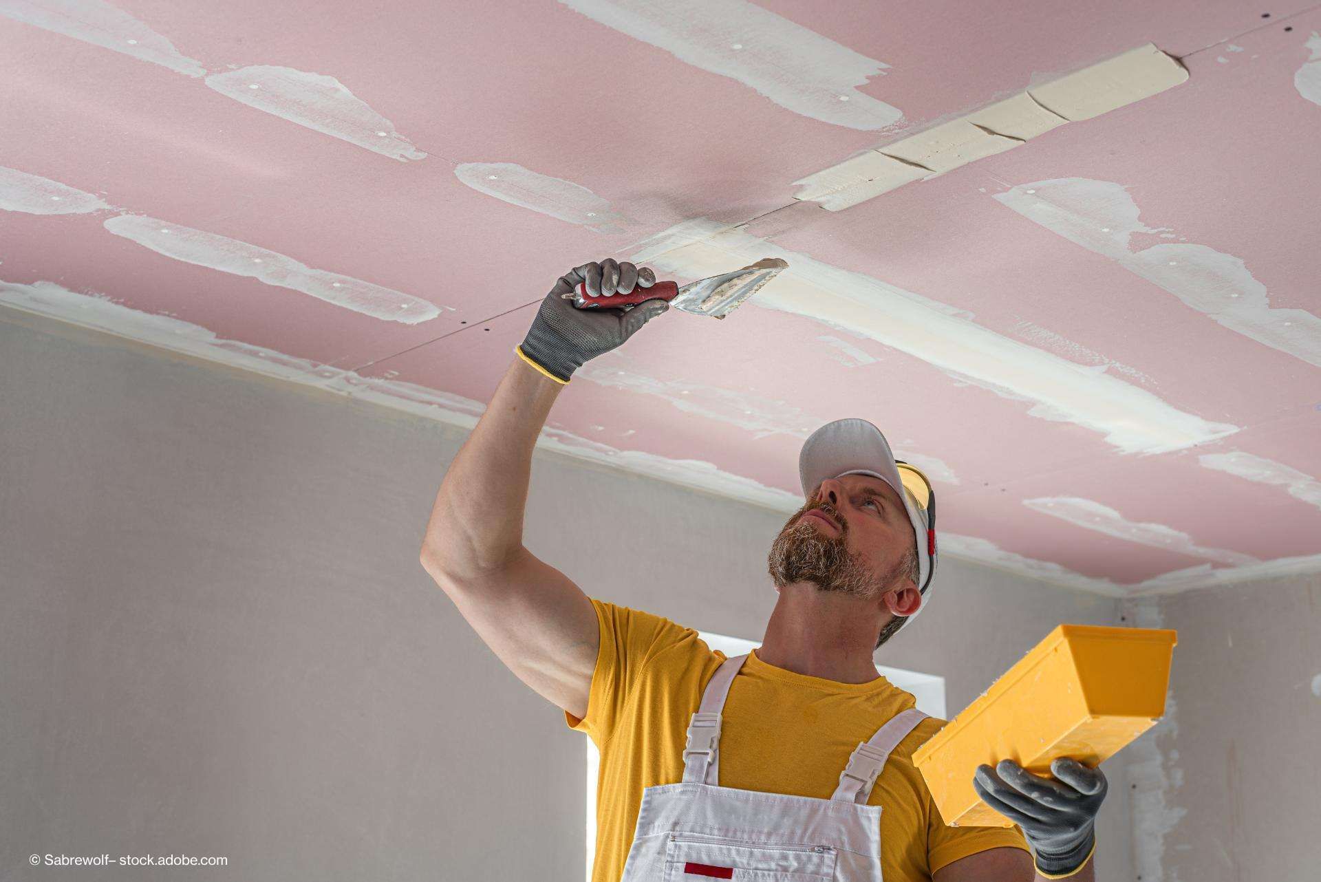 Ein Maler verputzt die Decke