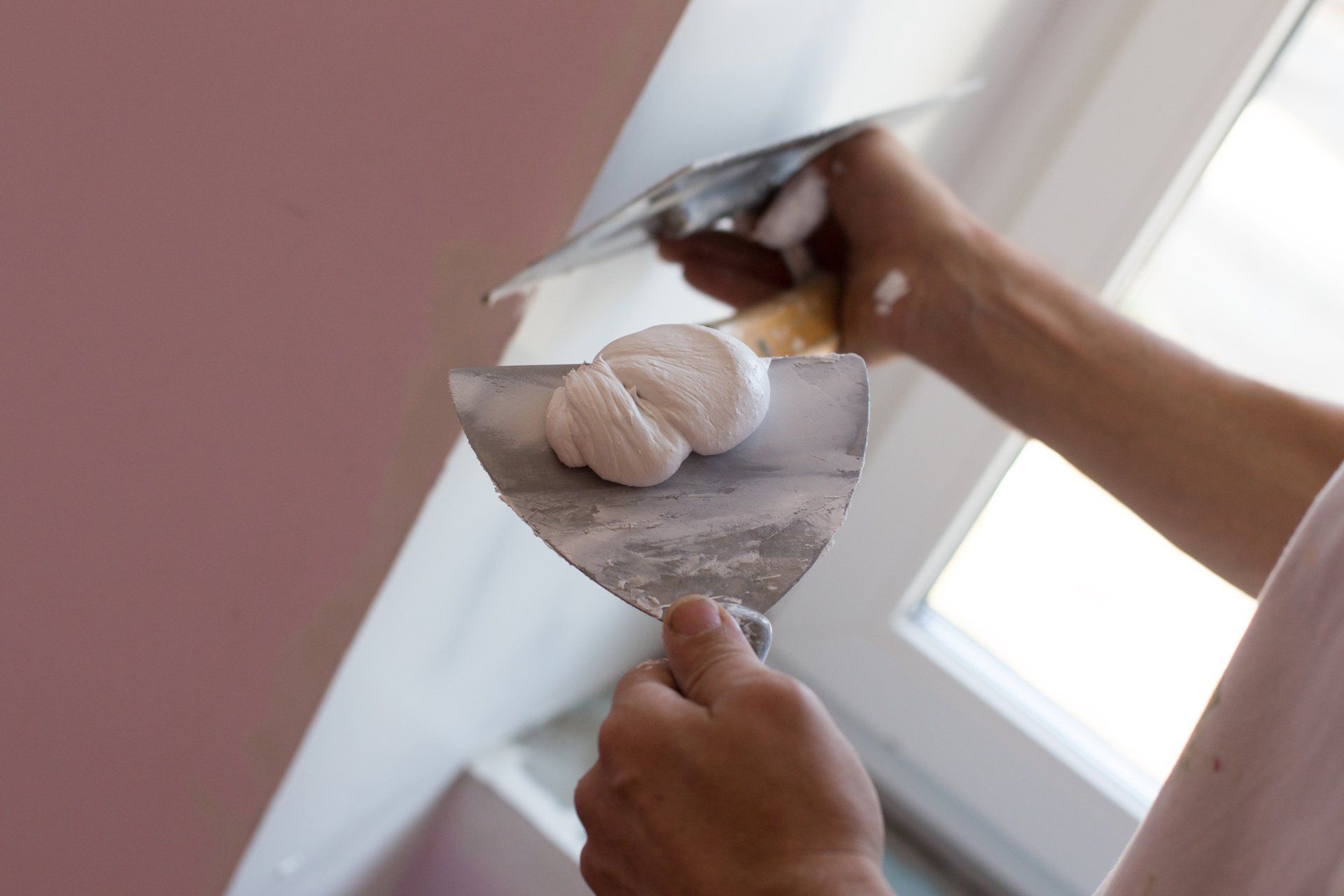 Pose d'enduit de rebouchage sur un mur à l'aide d'une truelle