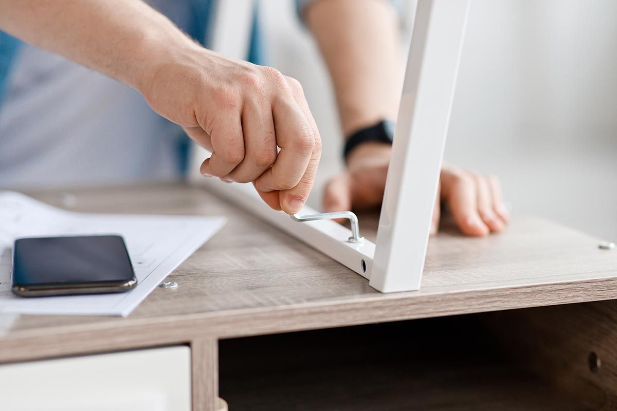 Focus sur un homme qui visse la patte d'un meuble