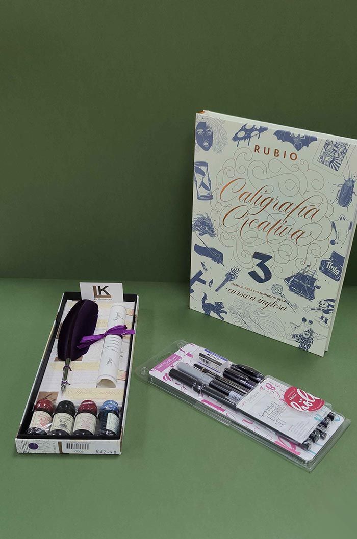 Tres artículos de cosmética sobre un fondo verde, que incluyen una caja con estampado floral, una pequeña caja negra y un tubo rosa.