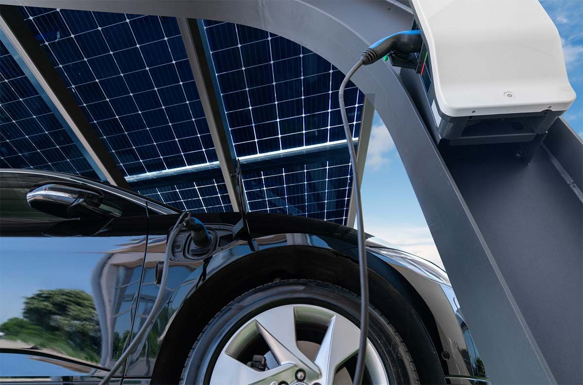Coche eléctrico negro cargándose bajo un panel solar.