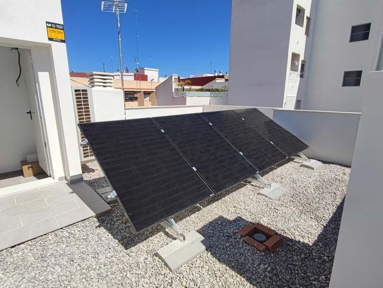 Paneles solares montados en un tejado, orientados hacia el sol, contra un cielo azul claro.