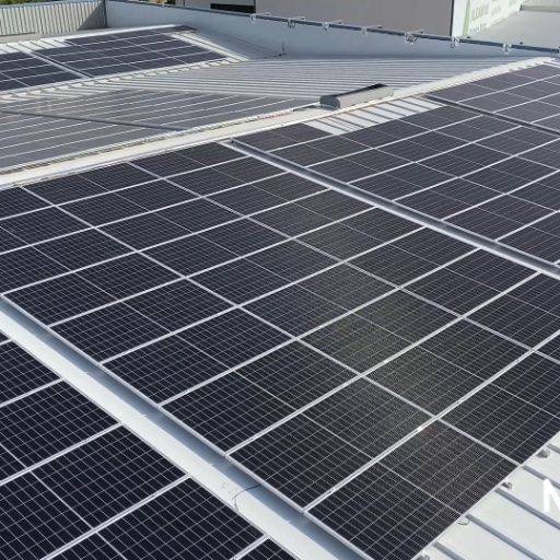 Paneles solares en la azotea de un edificio, dispuestos en filas. Paneles negros con líneas de cuadrícula blancas sobre un techo gris.
