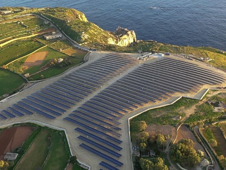 Conjunto de paneles solares en un campo costero, cerca del océano.