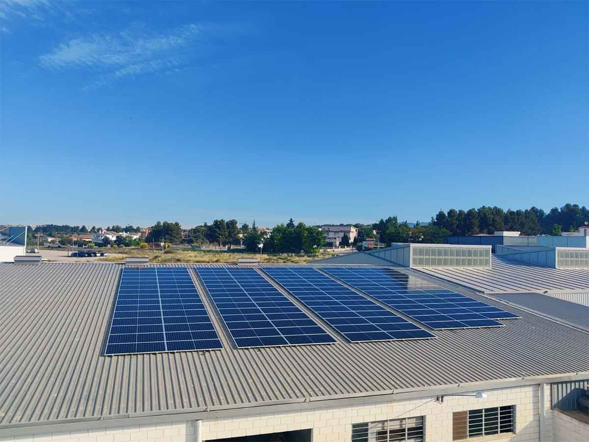 Paneles solares en el tejado de un edificio, bajo un cielo azul claro.