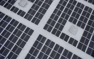Paneles solares sobre un tejado blanco, dispuestos en cuadrículas con varias pequeñas estructuras cuadradas blancas.