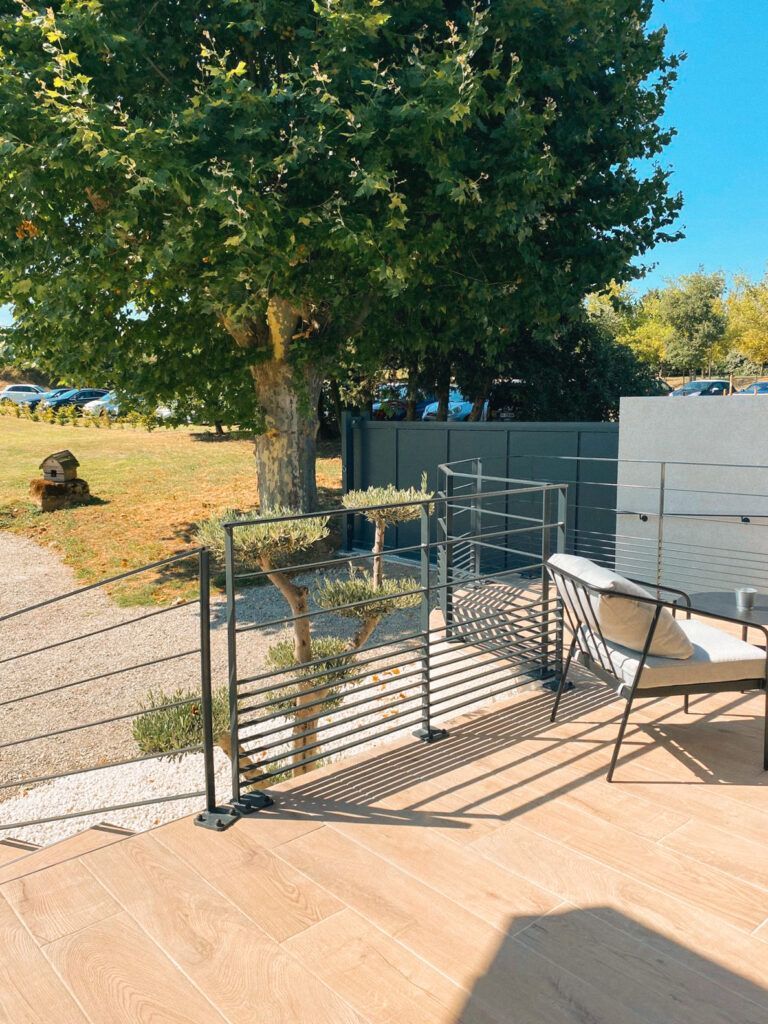 Terrasse avec rambarde en métal et chaises donnant sur un jardin