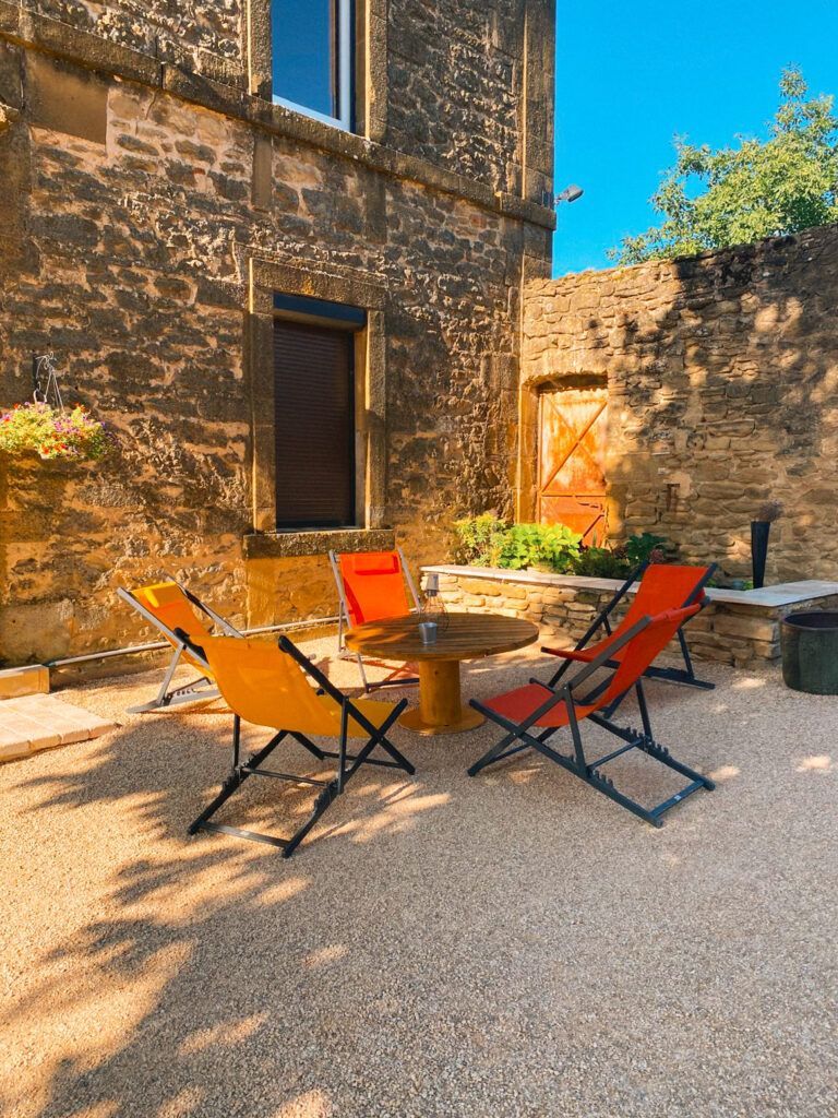 Terrasse extérieure avec chaises et table ronde près d'un muret en pierre
