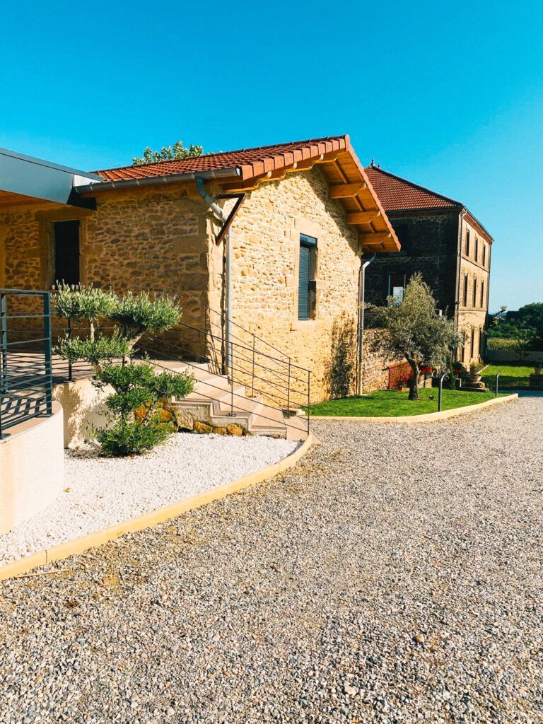 Maison en pierre au toit de tuiles, bordée d'un chemin de gravier