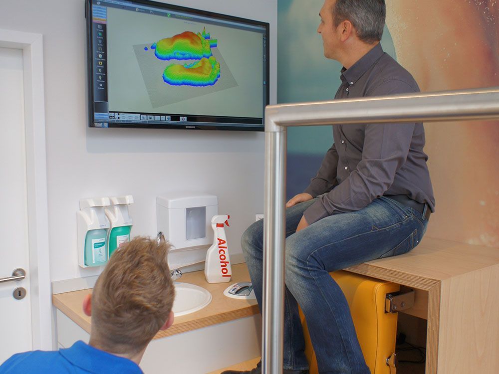 Ein Mann sitzt auf einem gelben Koffer und schaut auf einen Fernsehbildschirm