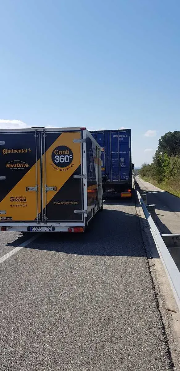 Dos camions circulen per una carretera, un al costat de l'altre.