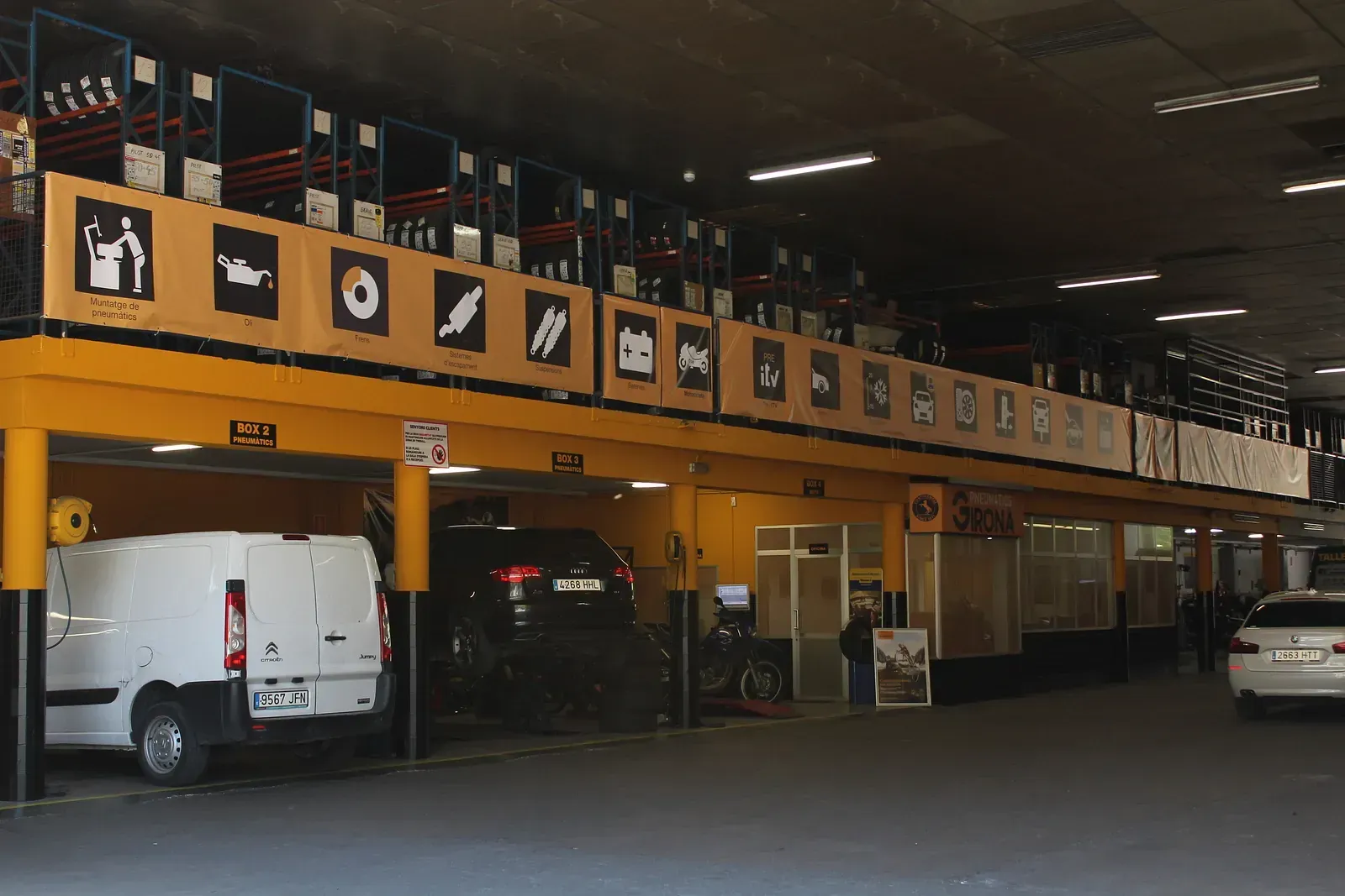 Una furgoneta blanca està aparcada sota un rètol groc en un aparcament.