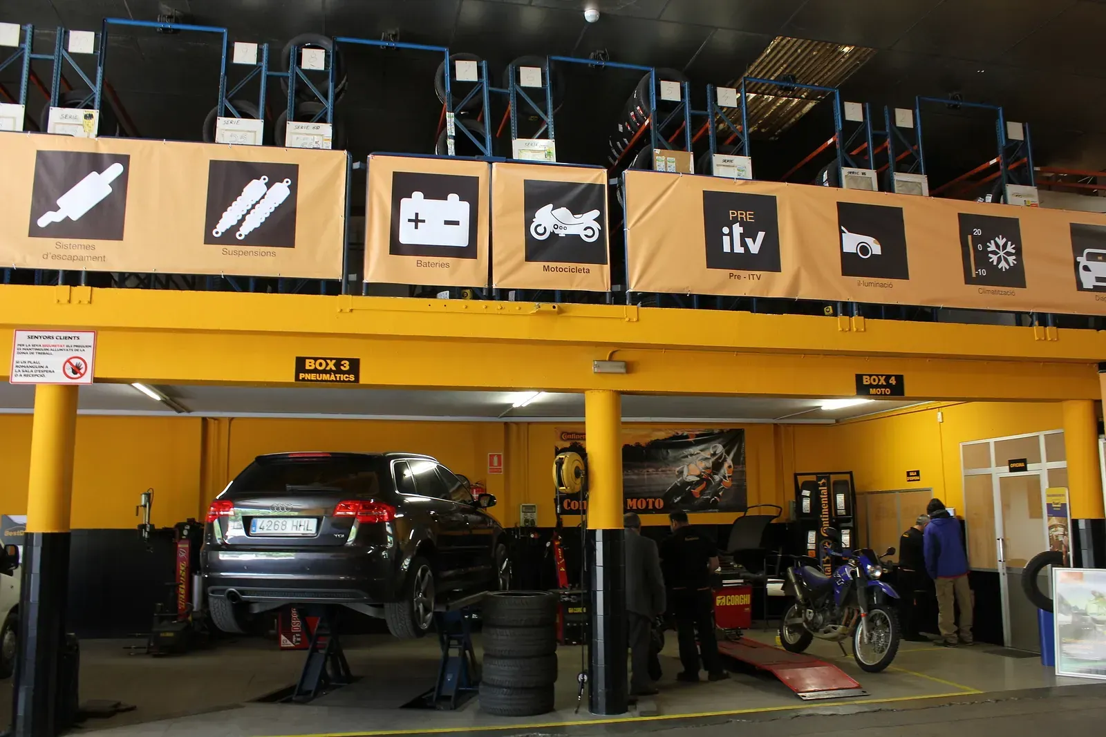 Un cotxe i una motocicleta estan sent reparats en un garatge