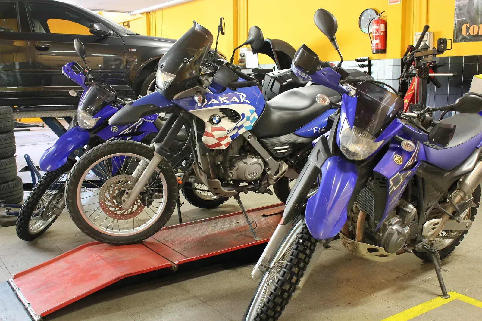 Una filera de motocicletes aparcades en un garatge al costat d'un cotxe