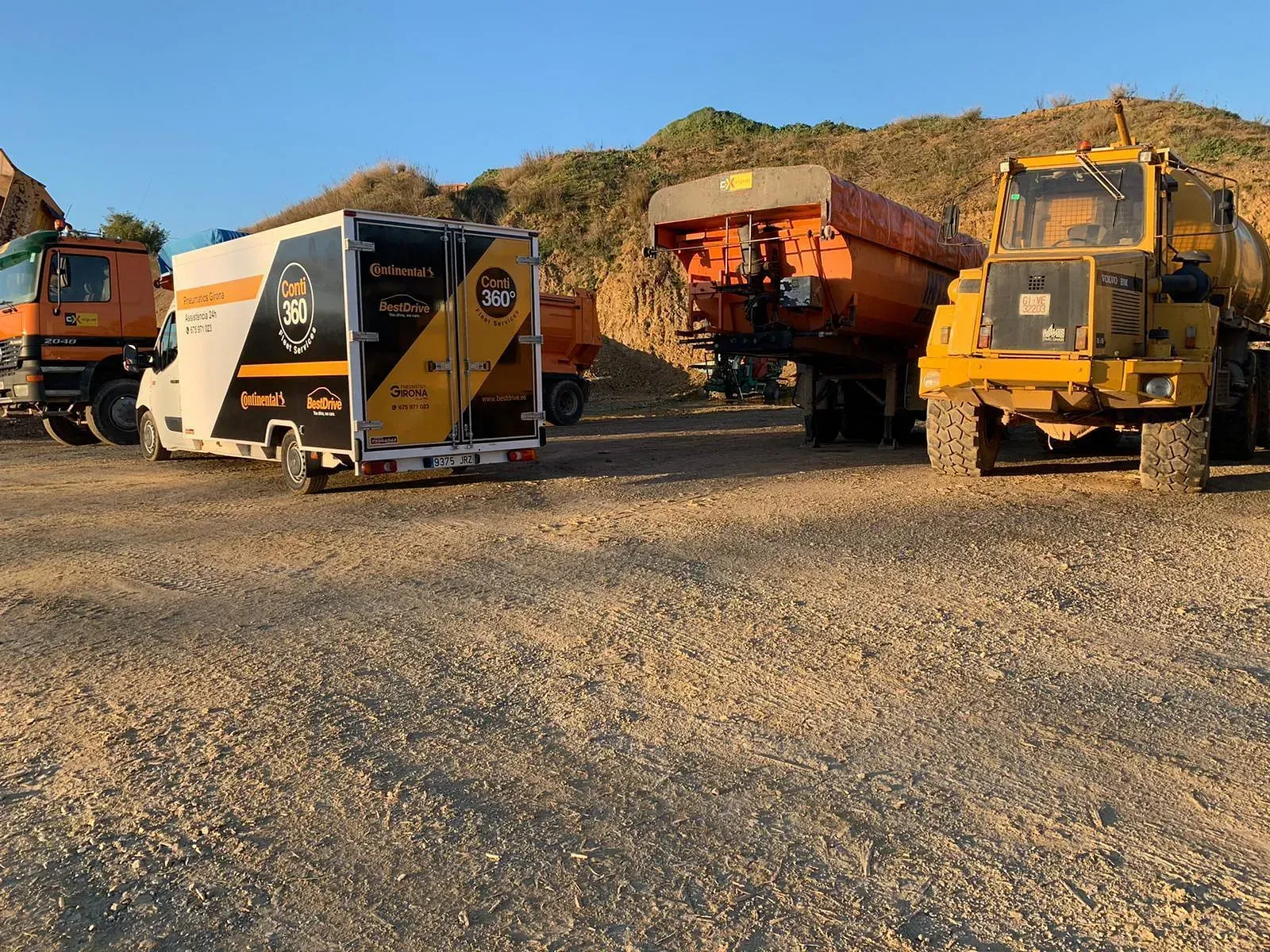 Una filera de camions està aparcat en un terreny de grava.
