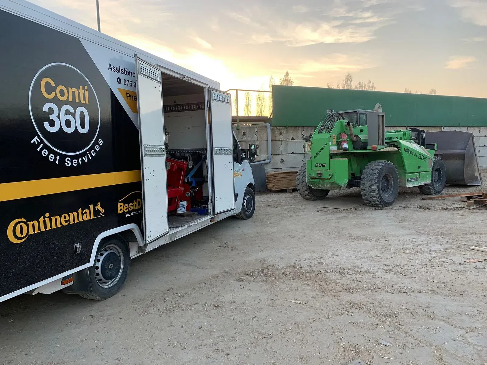 Un camió Continental està aparcat al costat d'una carretilla elevadora verda.