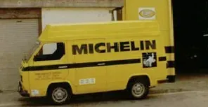 Una furgoneta Michelin groga està aparcada davant d'un edifici.