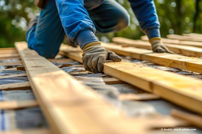 Zwei Zimmerer bauen eine Überdachung aus Holz