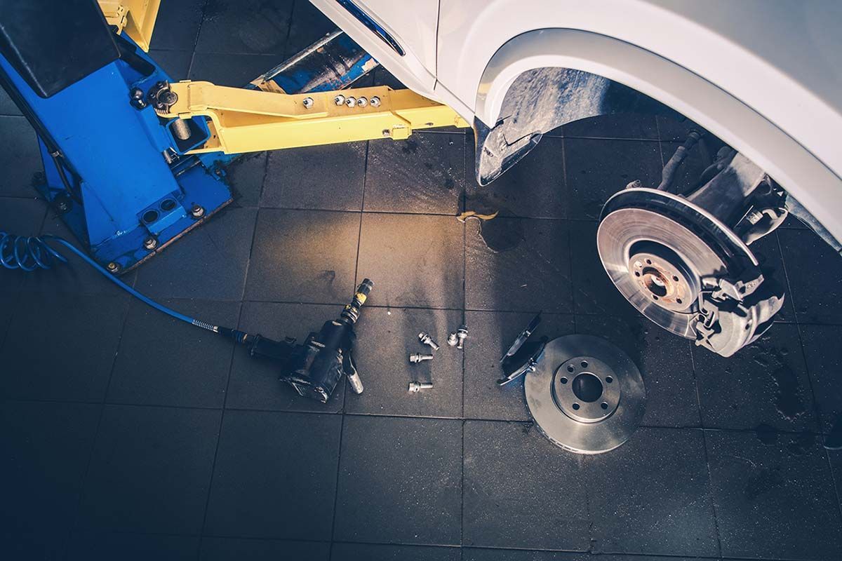 Un coche está siendo reparado en un elevador en un garaje.
