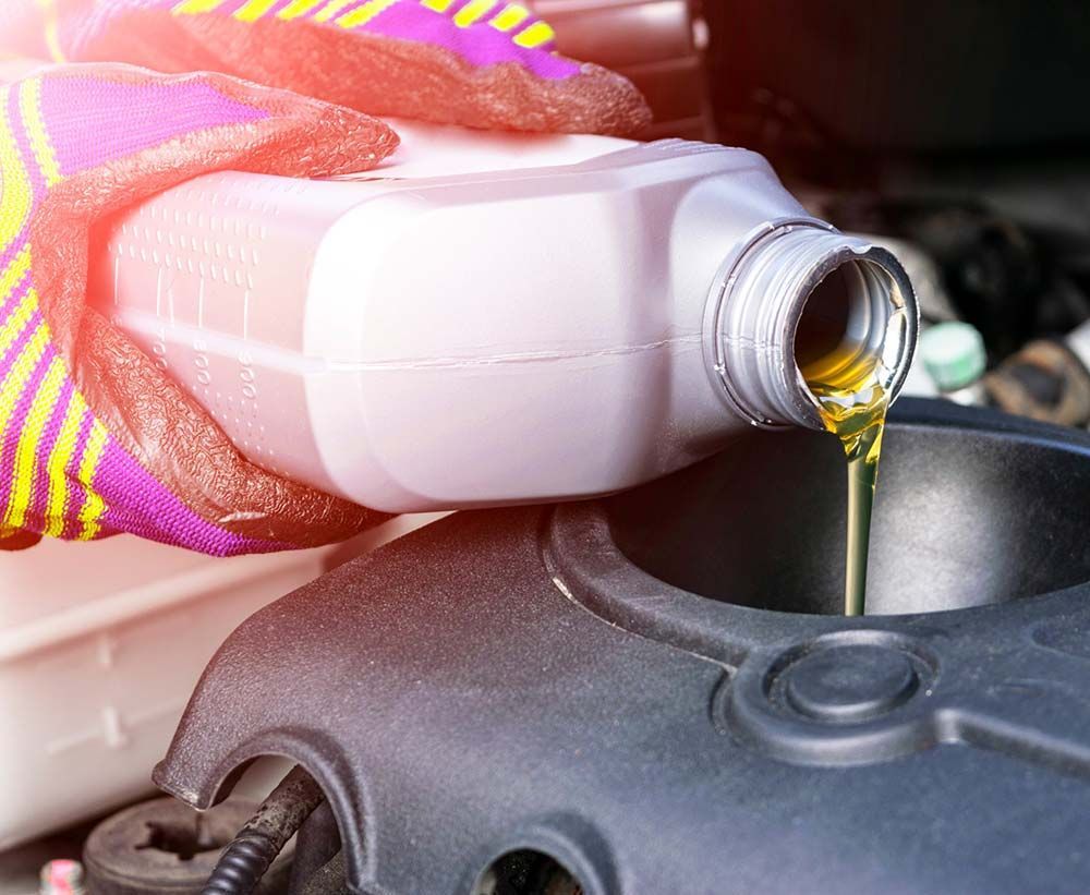 Una persona está vertiendo aceite en el motor de un automóvil.