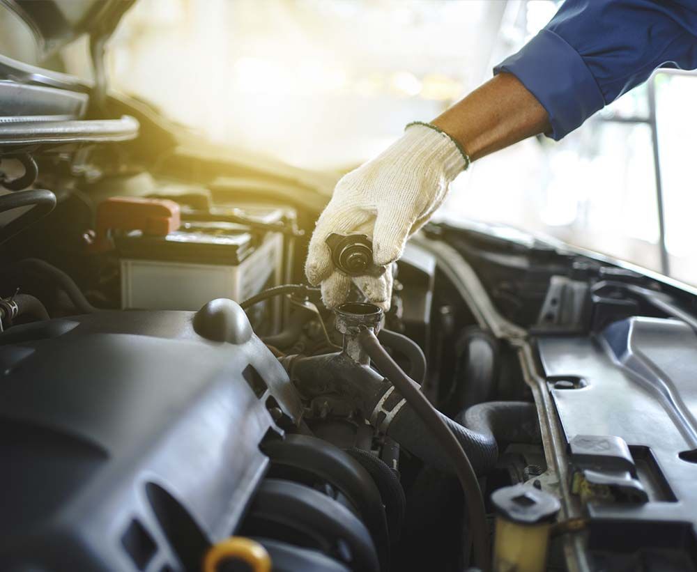 Un hombre está trabajando en el motor de un coche.