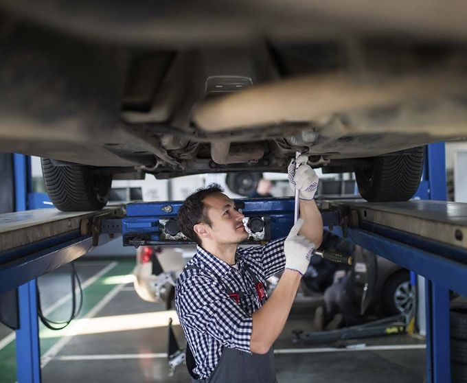 Un hombre está trabajando debajo de un coche en un garaje.