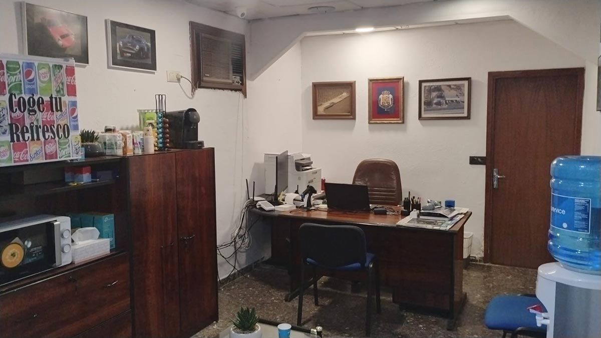 Una habitación con un escritorio, sillas y un dispensador de agua.