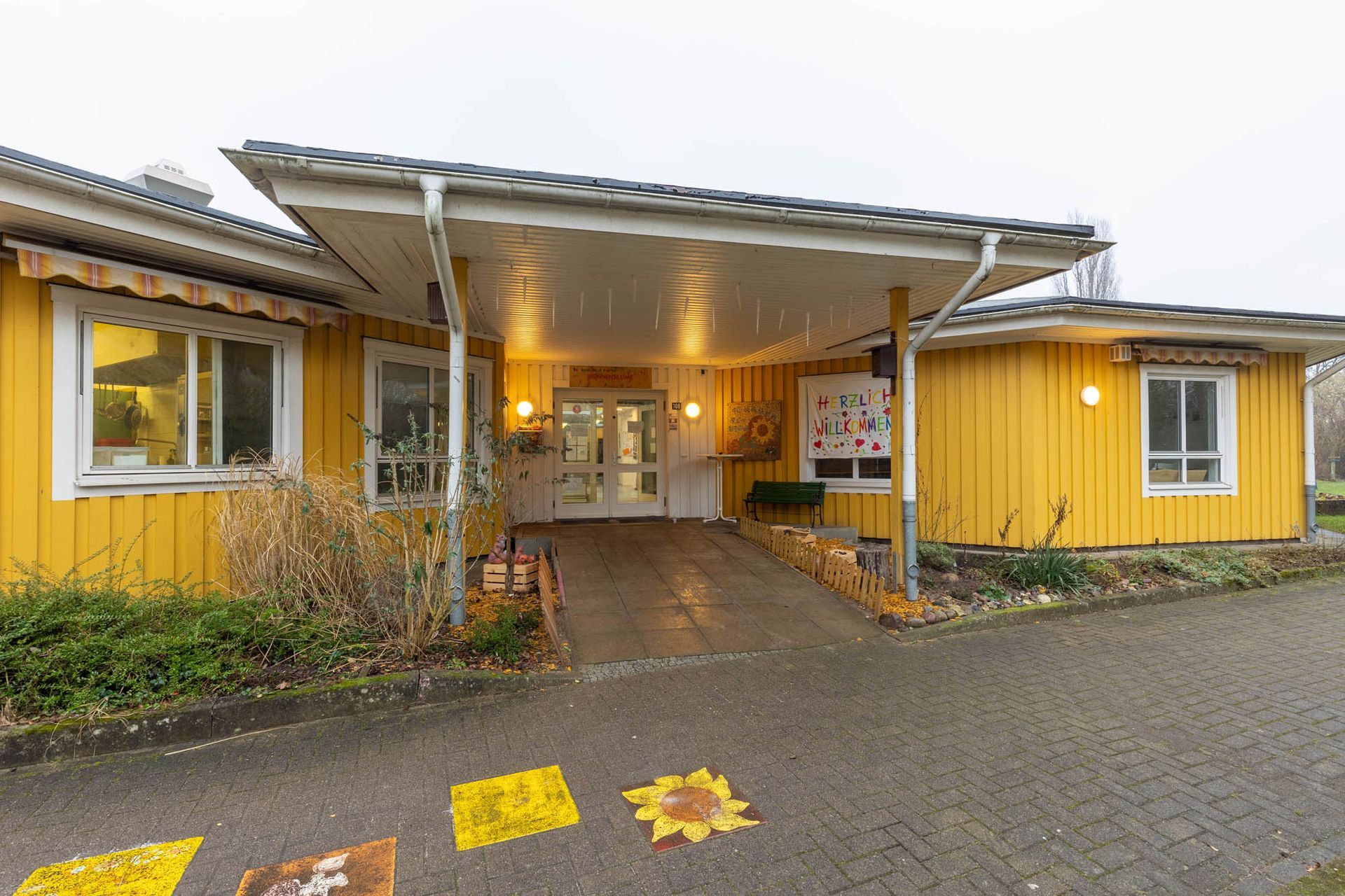 Ein gelbes Haus mit weißem Dach und einem Gehweg, der dorthin führt.