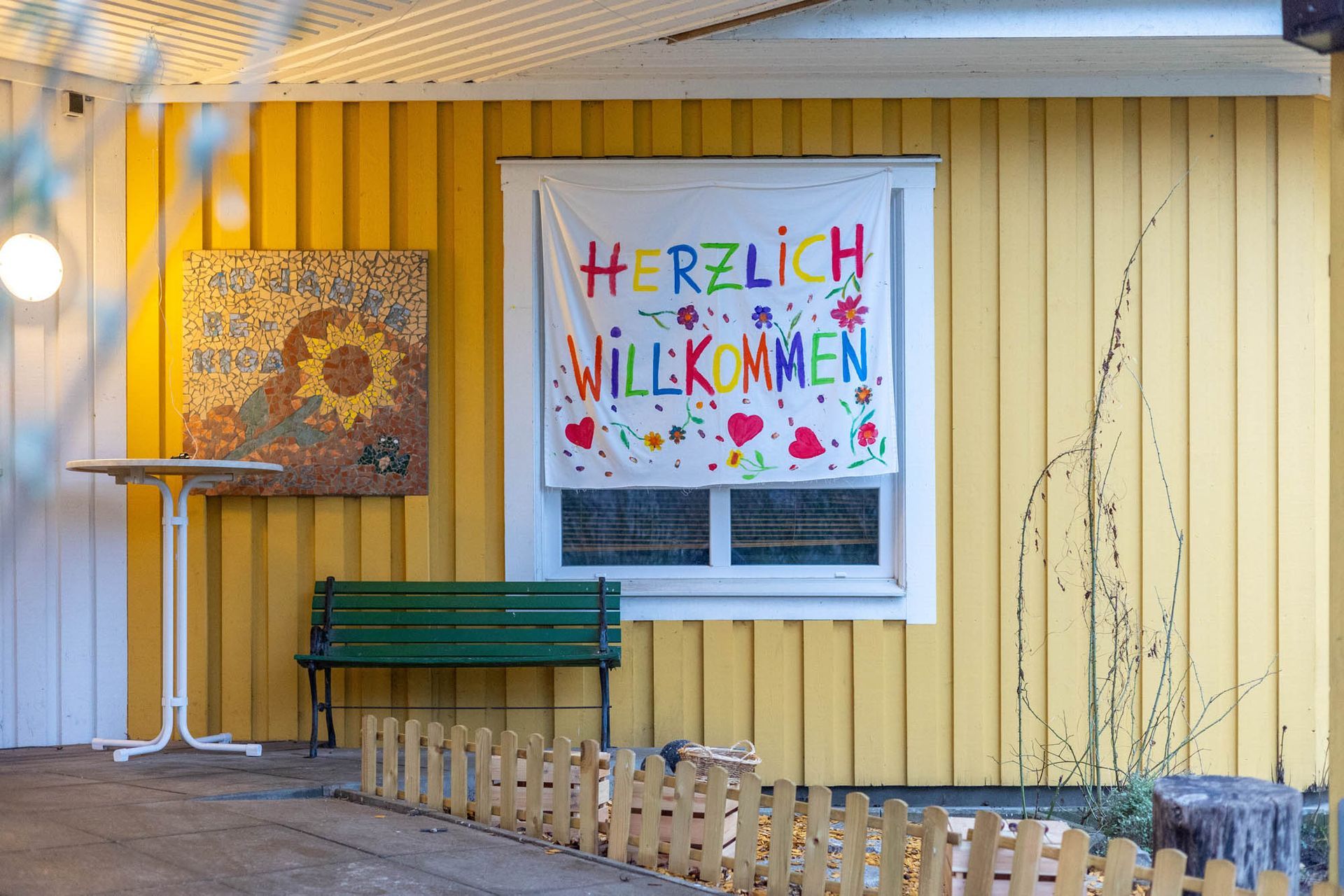 Ein gelbes Gebäude mit einem Schild mit der Aufschrift „Herzlich Willkommen“ darauf.