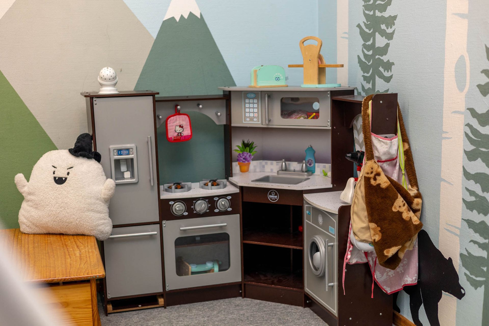 Eine Kinderspielküche mit Kühlschrank, Herd, Spüle und Mikrowelle.