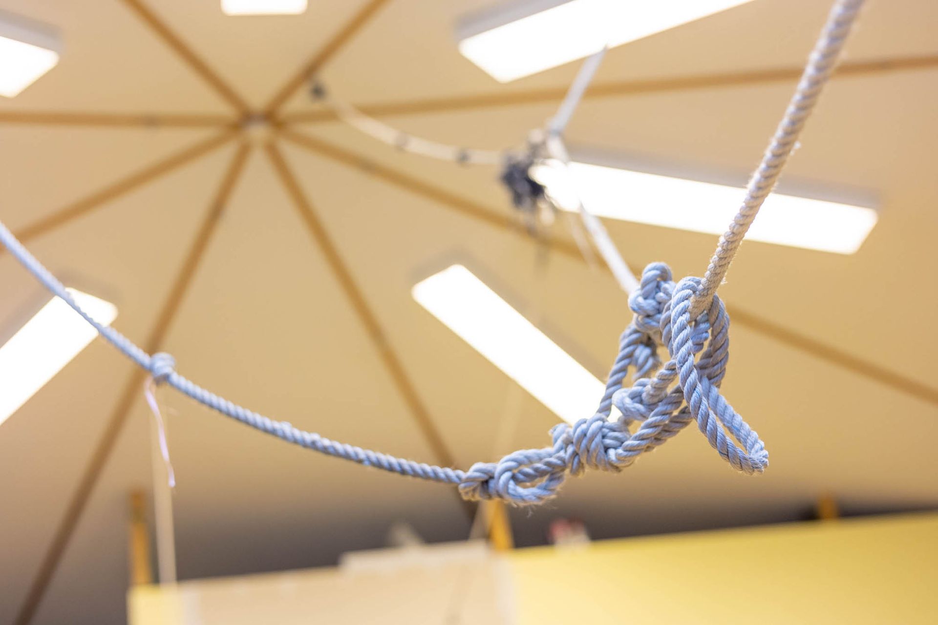 Ein blaues Seil mit einem Knoten in der Mitte hängt von der Decke